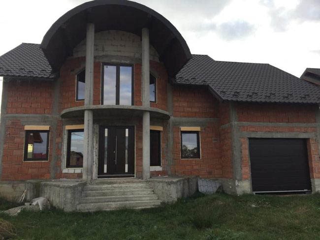 Casa din caramida rosie si acoperis gri cu ferestre si usi termopan maro montate de ifenster beclean