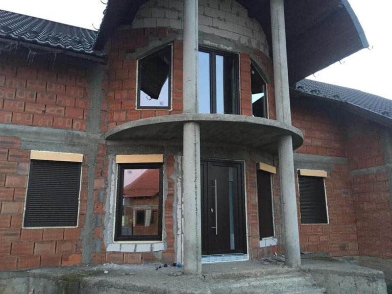 Casa din caramida rosie si acoperis gri cu ferestre si usi termopan maro montate de ifenster beclean